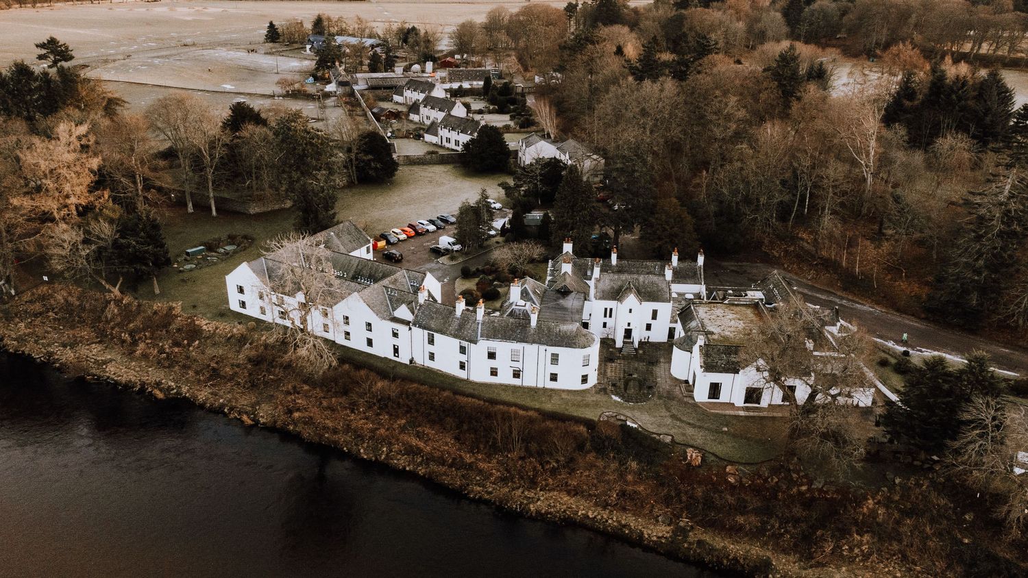 Drone shot of white buildings and houses situated along a curved riverbank.