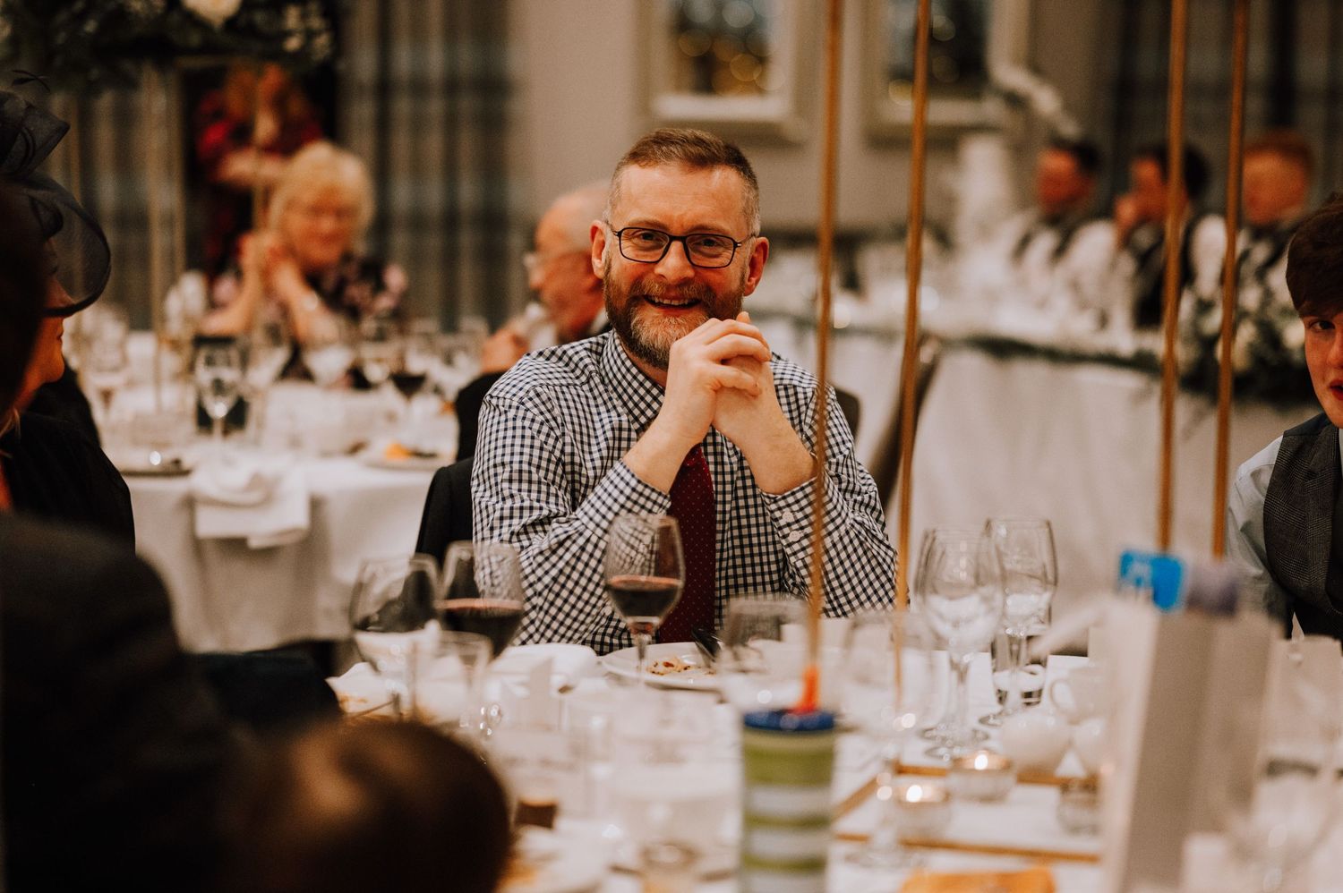 Guest listening intently during wedding reception dinner with elegant table settings.