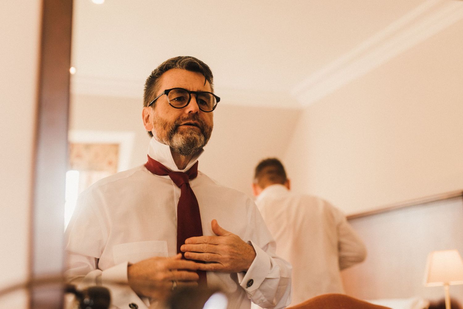 Person adjusting formal attire while getting ready in room.