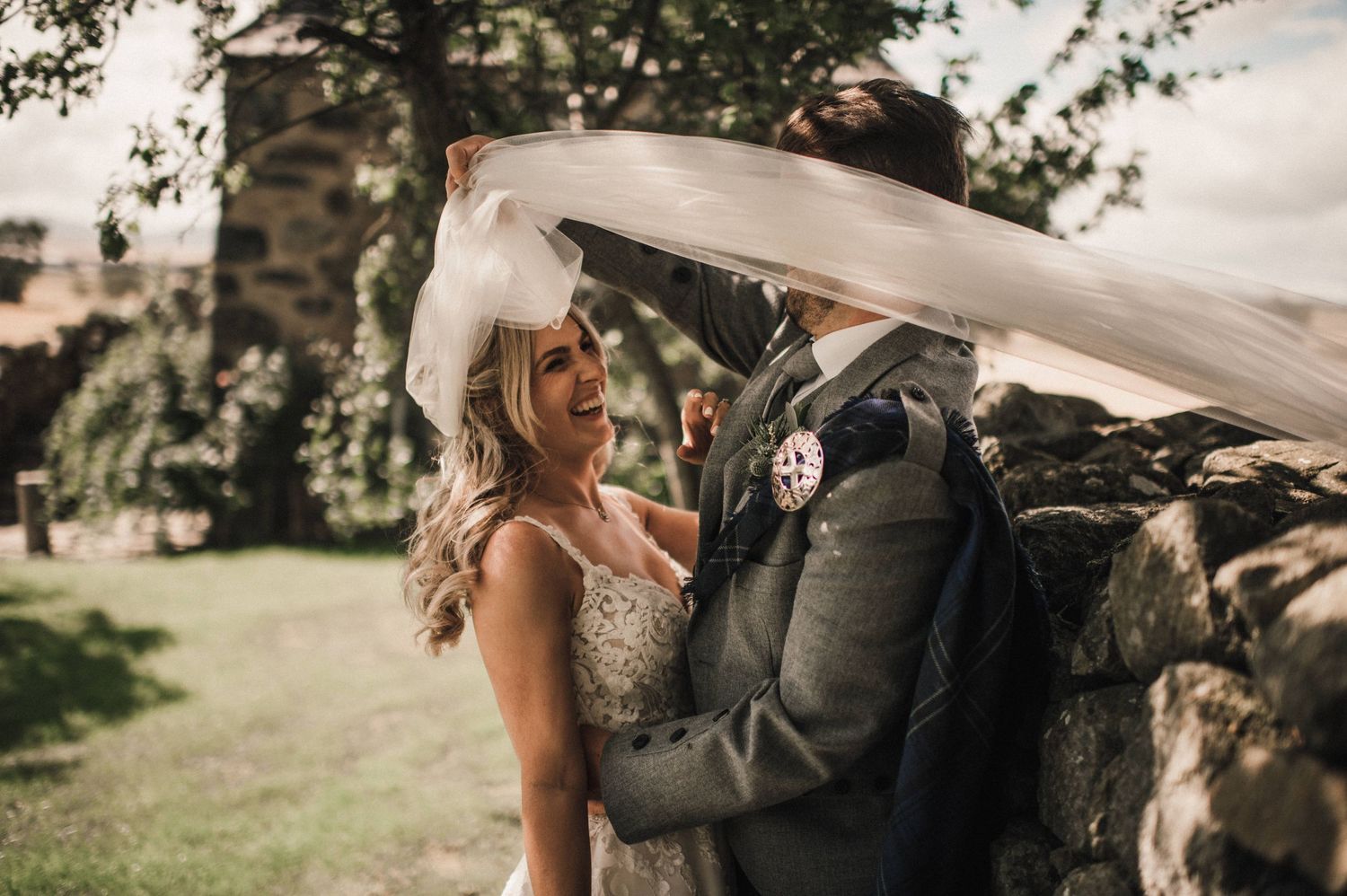 Long flowing veil catches the breeze during intimate wedding moment.