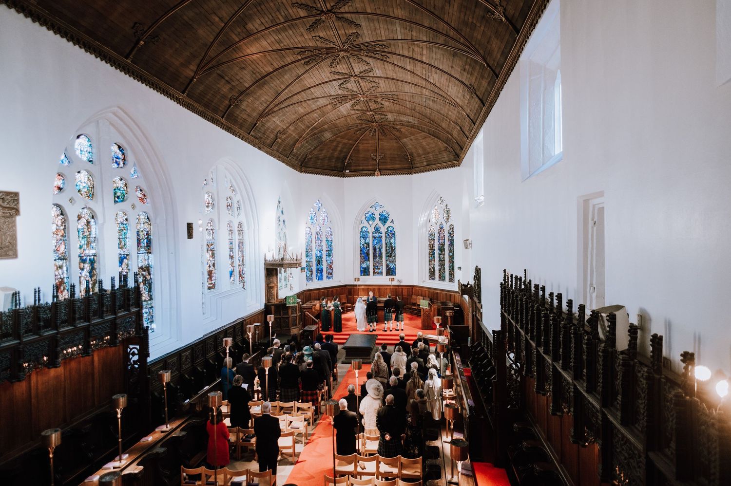 Overhead view of wedding celebration in traditional church with wooden beams and stained glass.