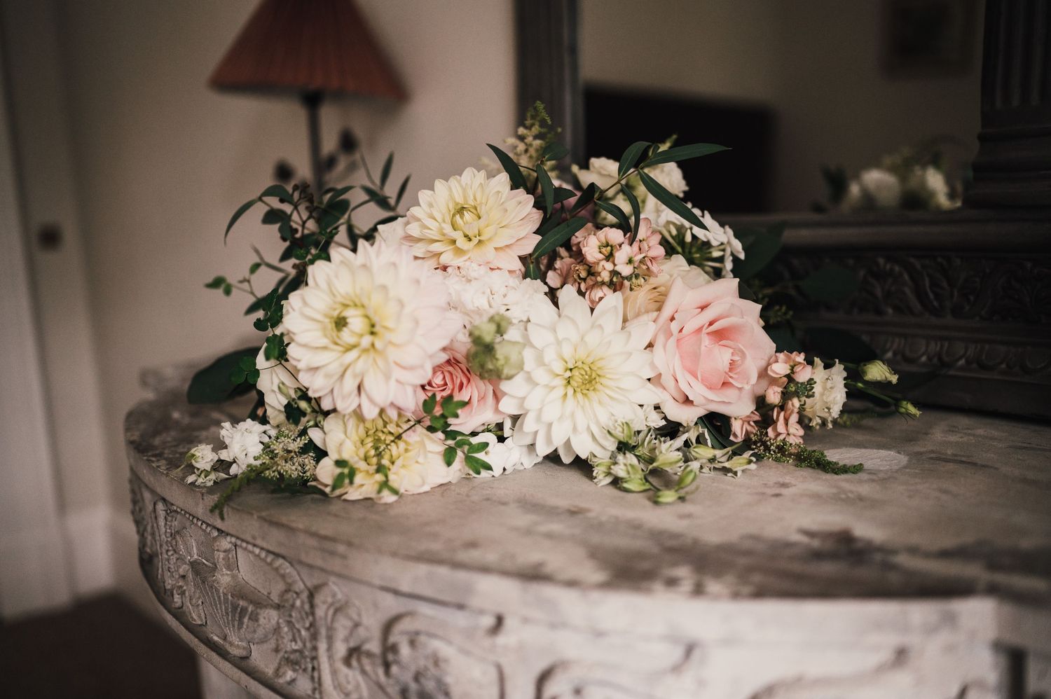 Soft pink and white dahlia flowers arranged on a rustic table surface.