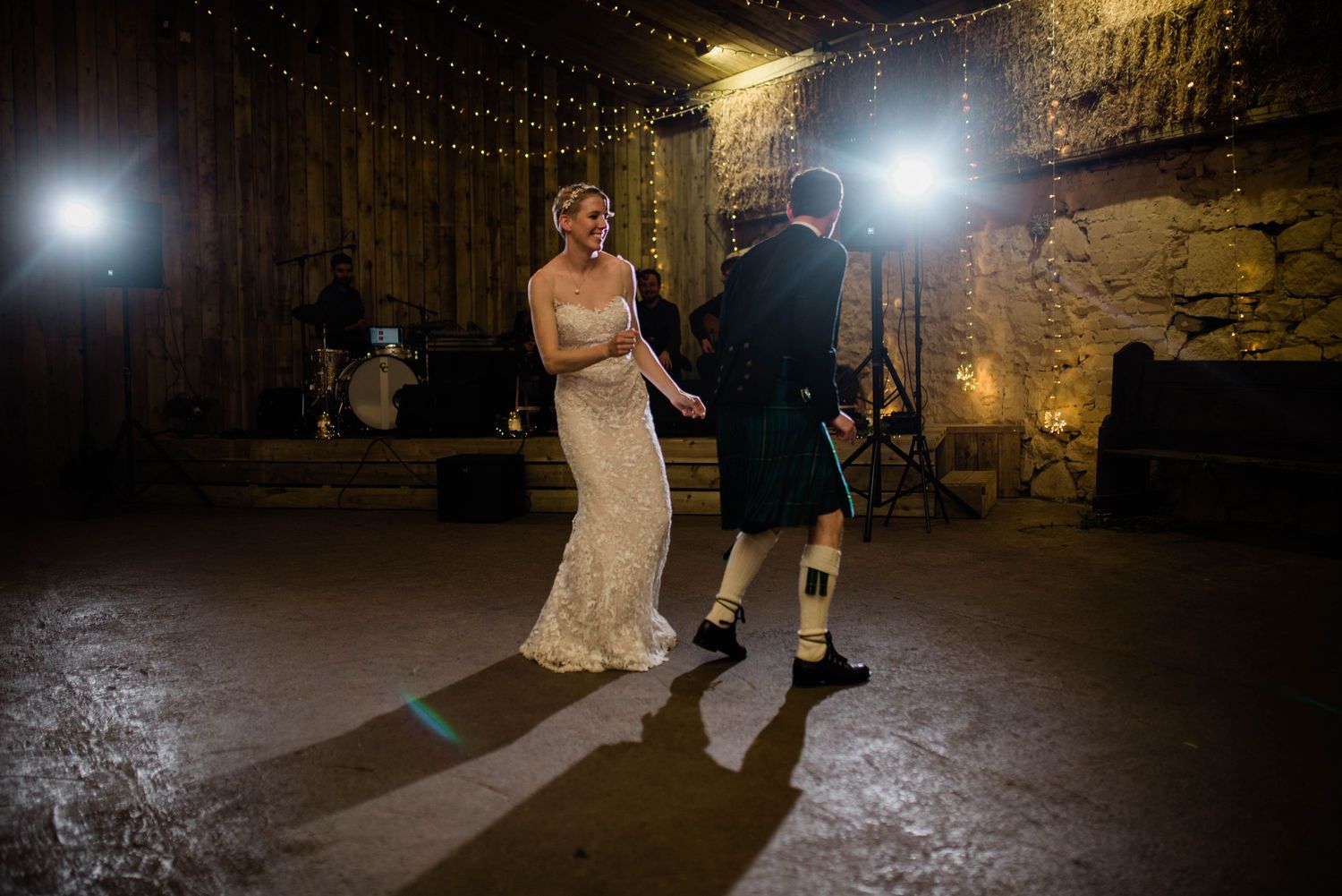A couple performs their first dance at a wedding reception in a rustic venue with atmospheric lighting.