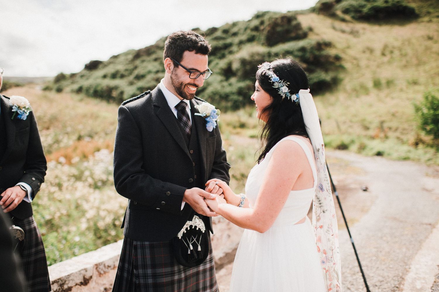 A tender moment during a Scottish wedding ceremony as the couple exchanges rings on a stone bridge.