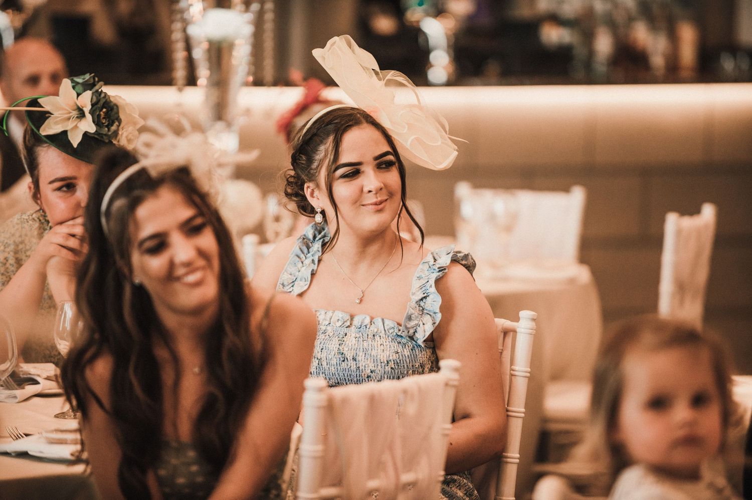 Wedding reception guests seated at decorated tables sharing joyful moments.