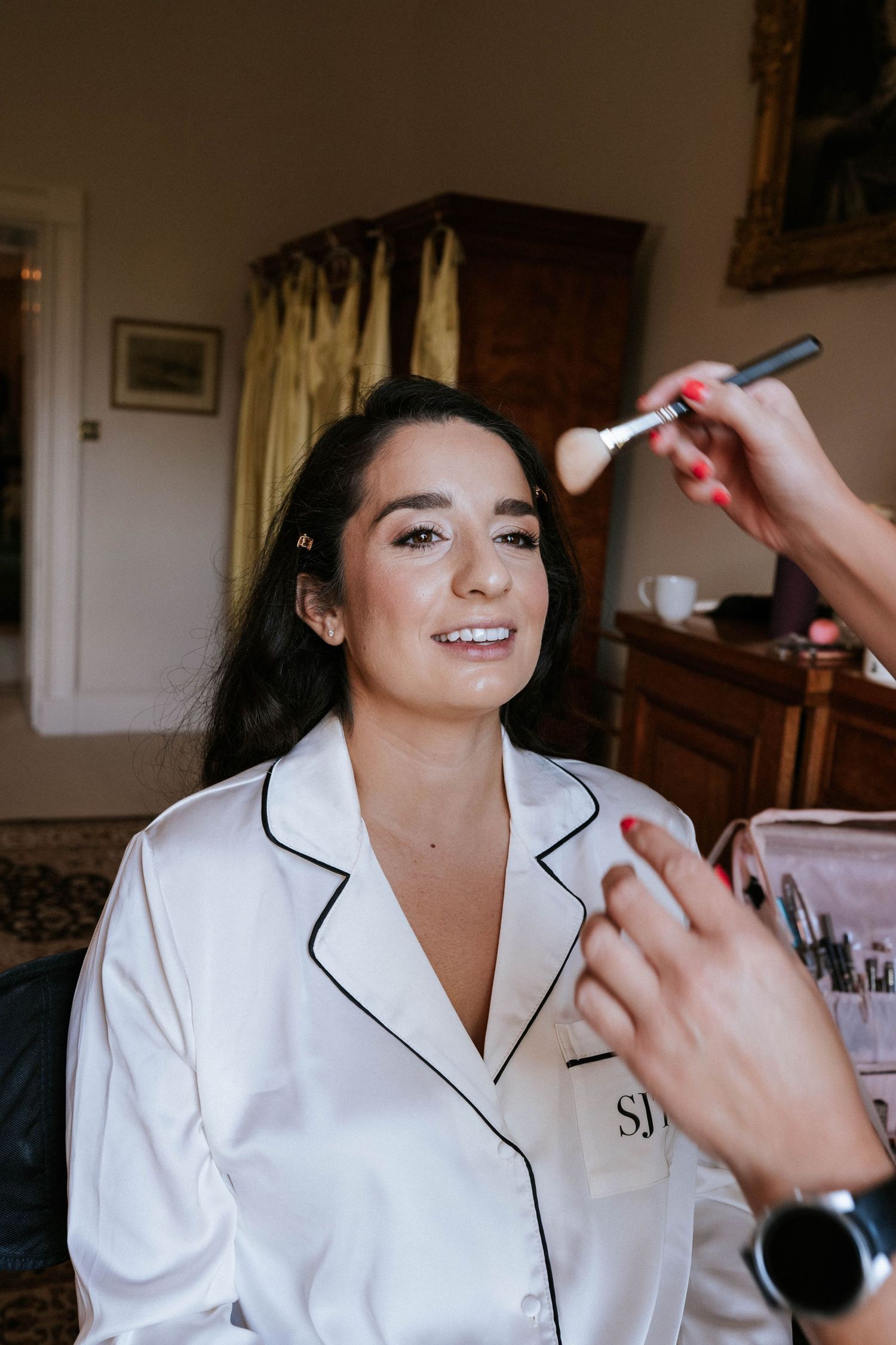 Getting ready scene with makeup application in white satin robe.