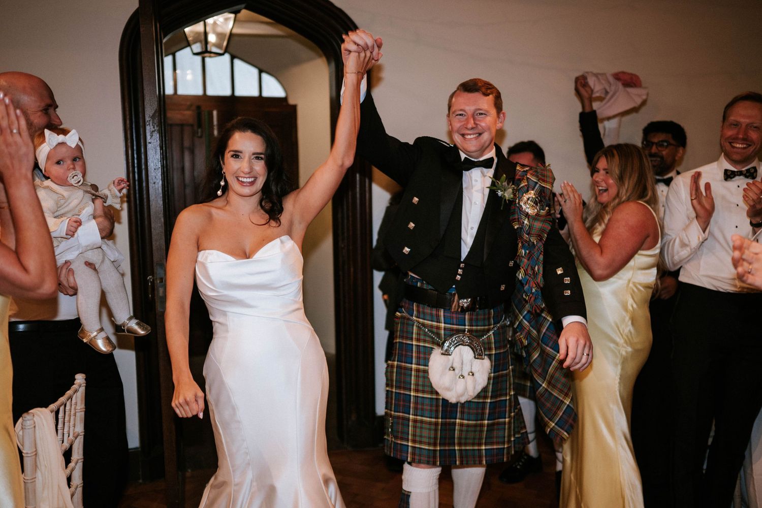 Wedding party dancing and celebrating at an indoor reception with joyful energy.