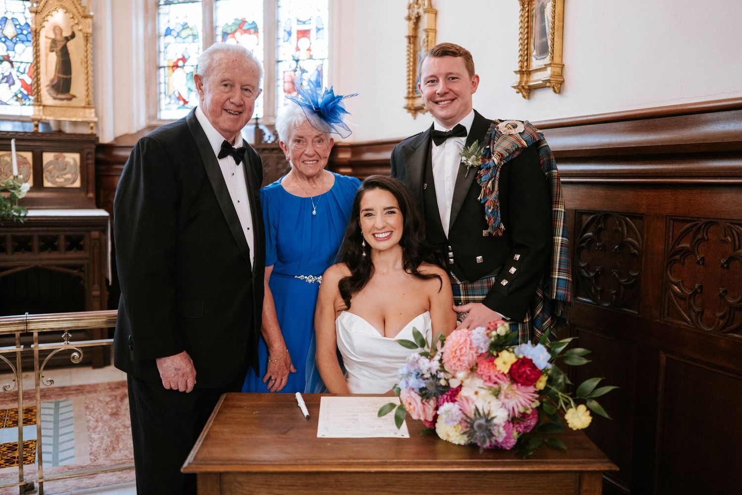Wedding ceremony signing moment in an elegant church interior with ornate decor and colorful floral arrangements.