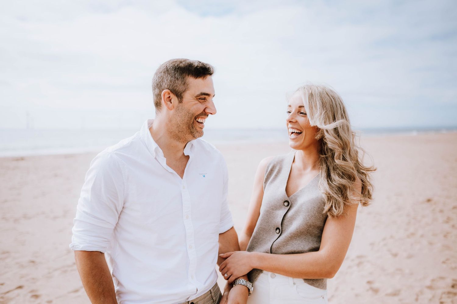 Engagement photography session Aberdeen. A couple shares tender moments on a sandy beach during a bright afternoon.