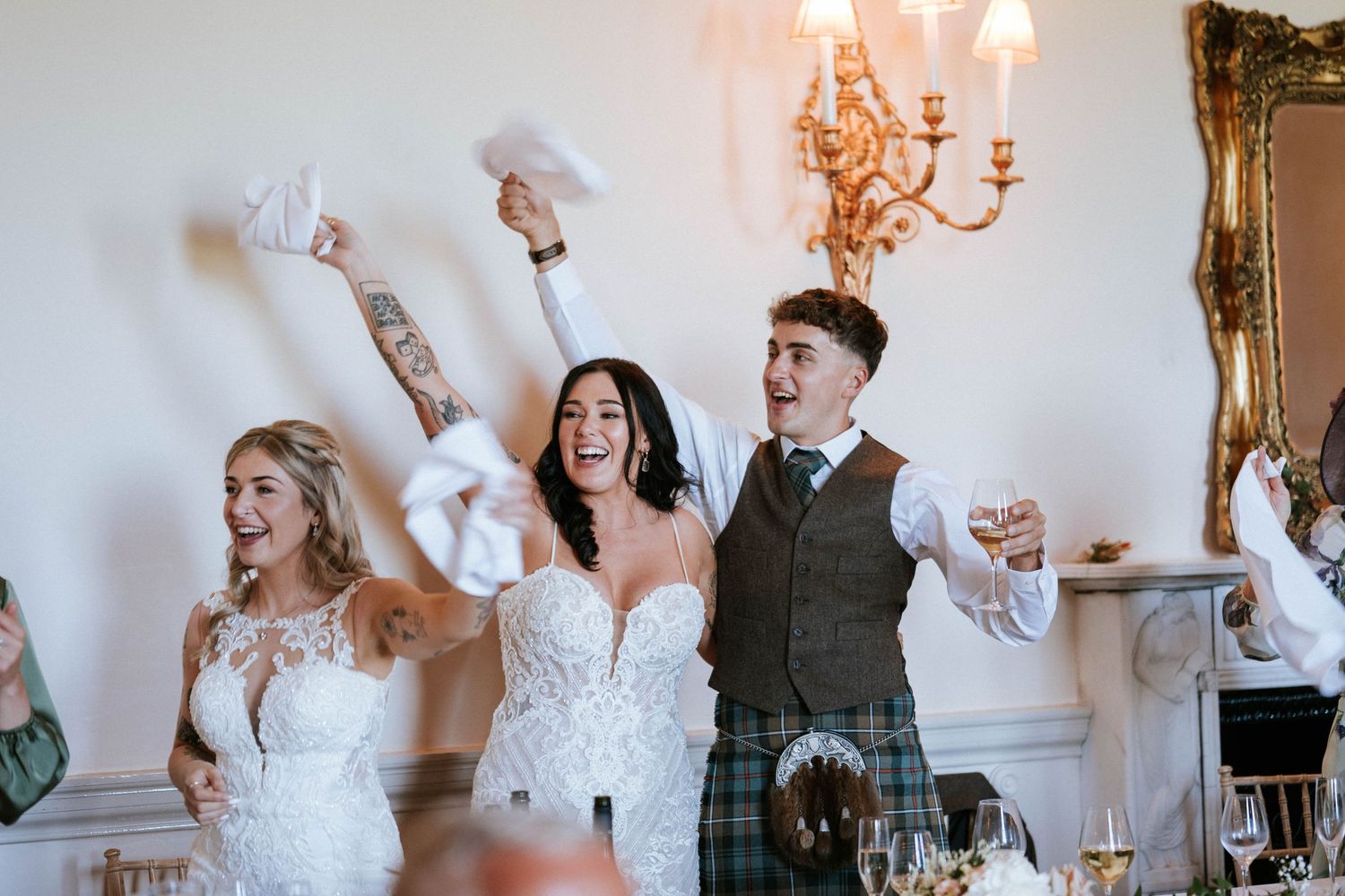Aberdeen Wedding Photography. Wedding celebration with guests cheering and waving napkins in an elegant reception hall.