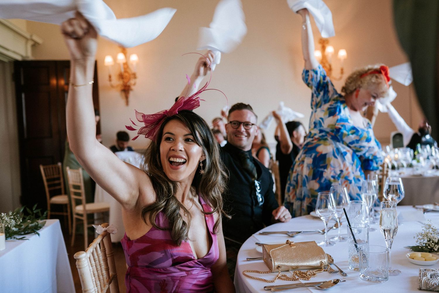 Guests raising their hands in celebration during a wedding reception.