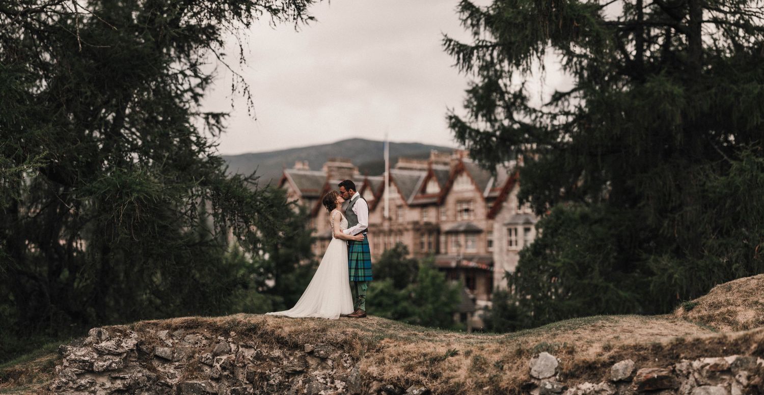 Romantic wedding portrait silhouetted against historic mansion in background.