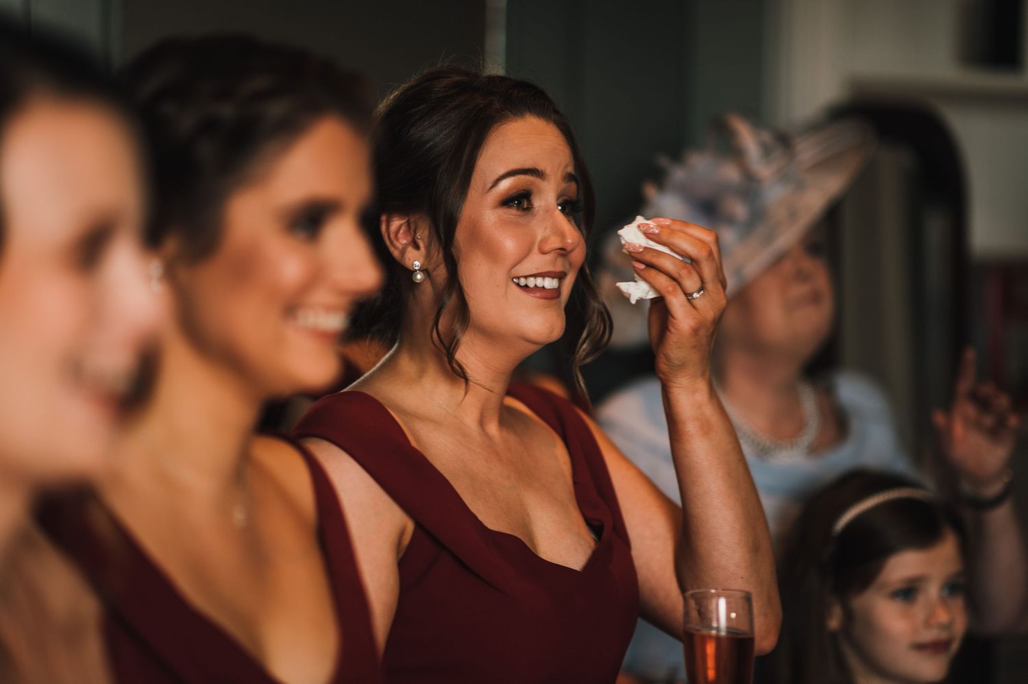 Bridesmaids in burgundy dresses share a joyful moment during celebrations.