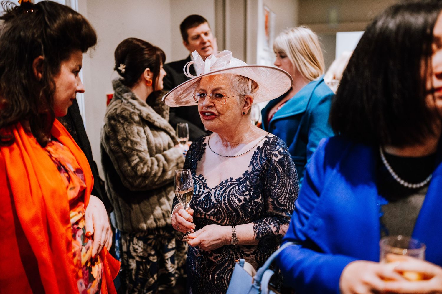 Wedding guests enjoying conversation and drinks at a lively indoor reception.