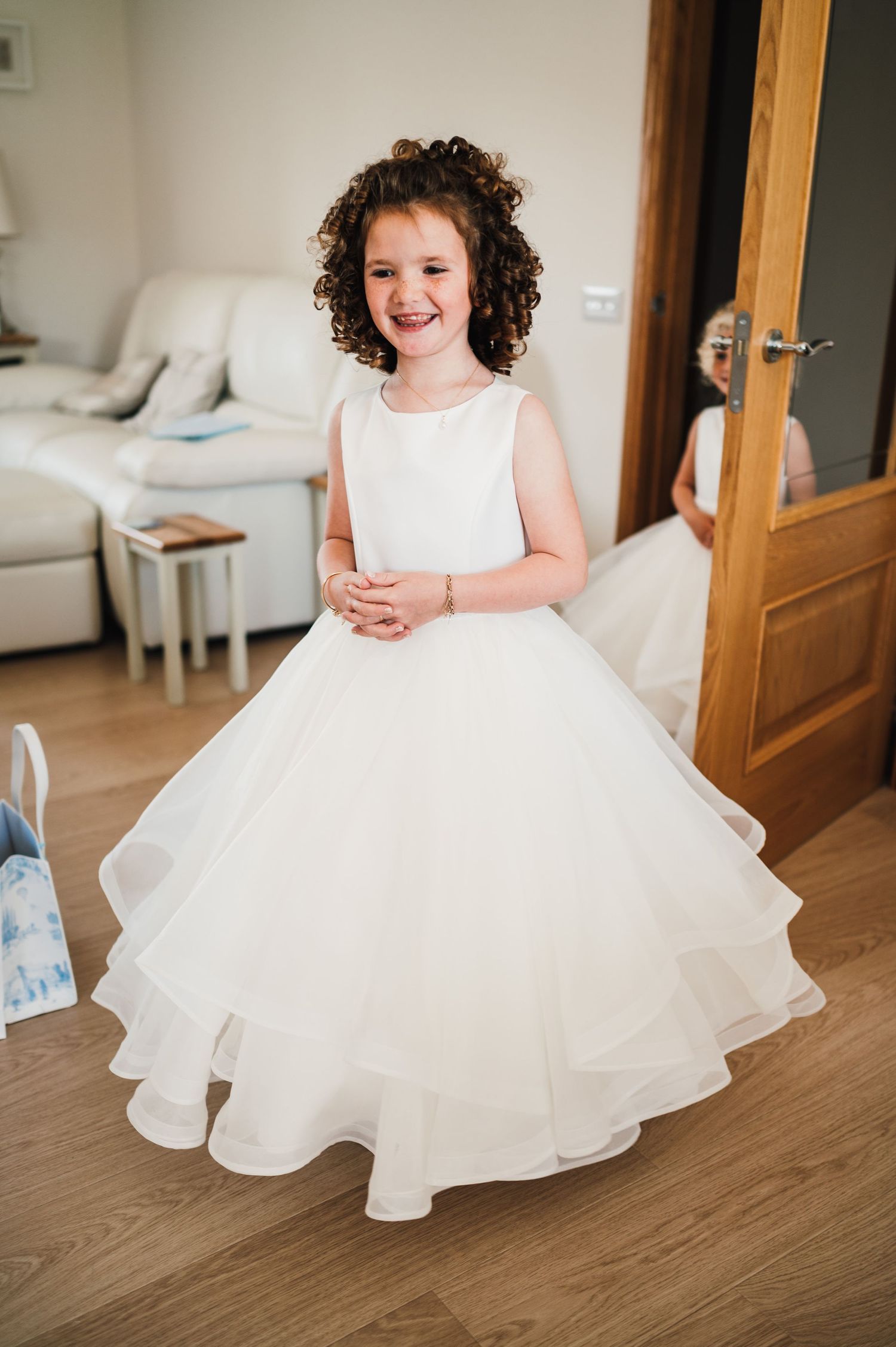 Young attendant wearing a stunning white layered dress poses in a living room setting.