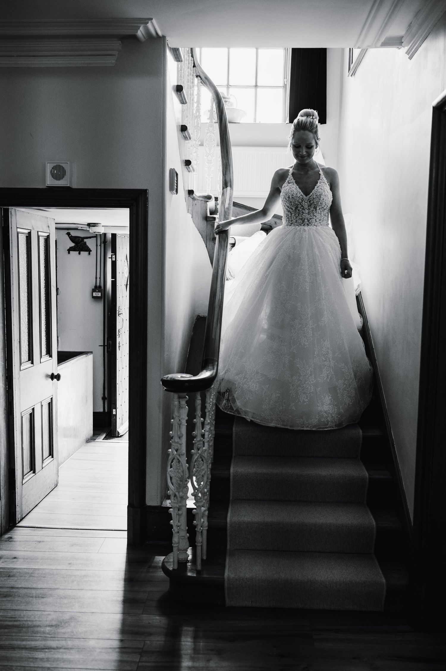 Black and white image of bride in ballgown on ornate staircase with dramatic lighting.