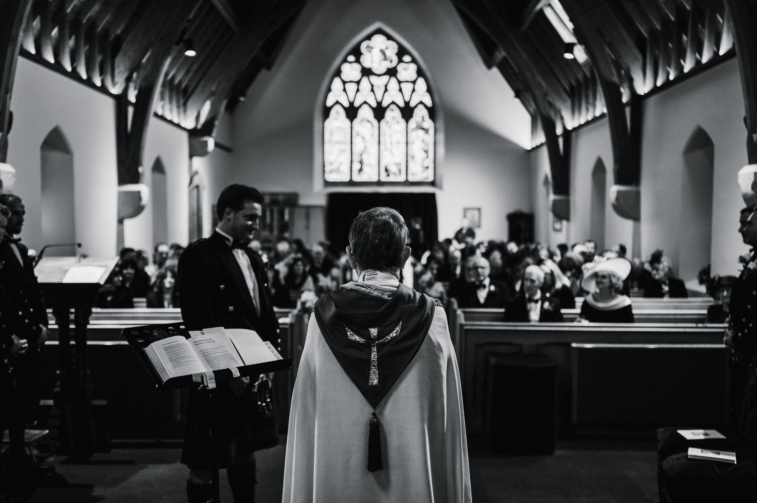 Black and white photo of traditional Scottish wedding ceremony inside historic church.