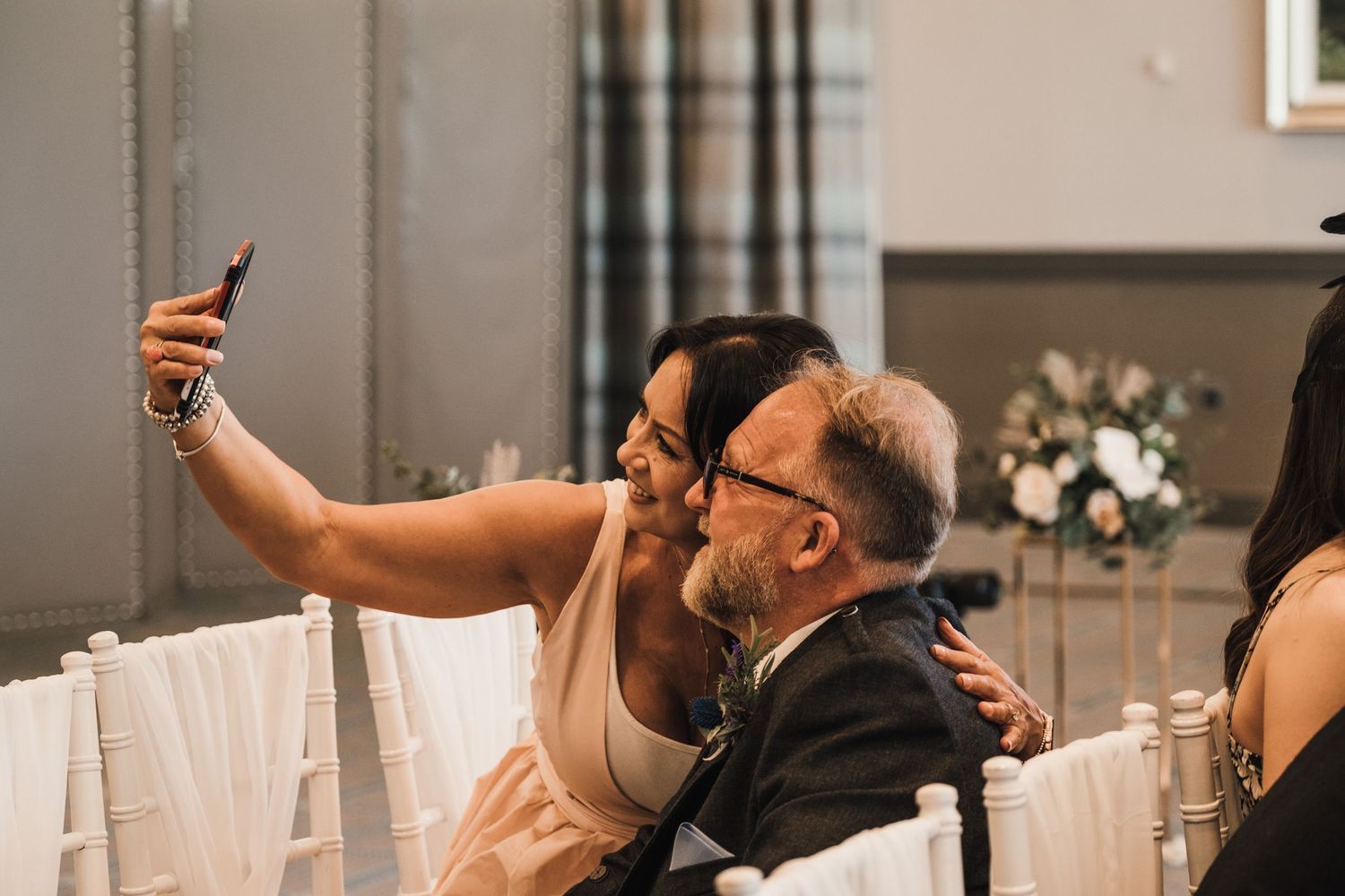 Wedding guests taking a selfie during reception celebrations with decorative curtains behind them.