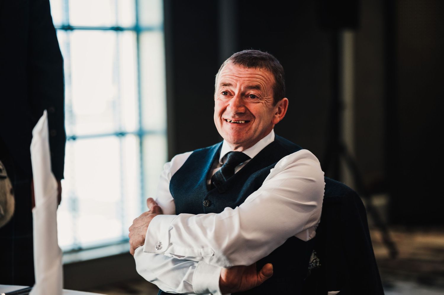 A formal event guest in a vest and tie smiles warmly at the camera.