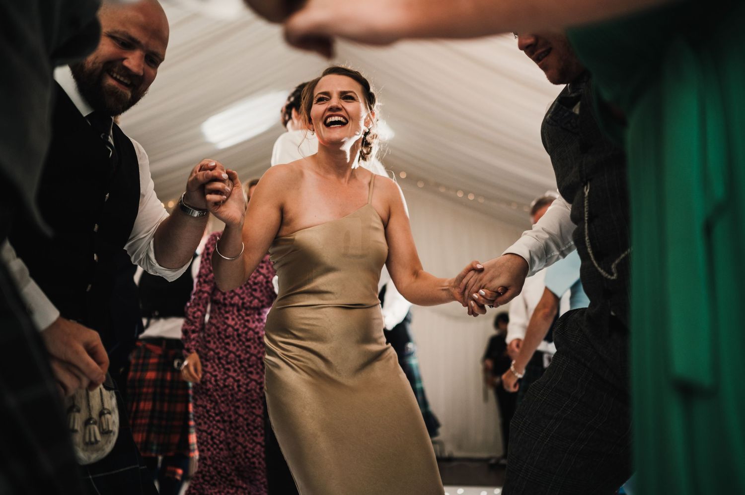 Joyful celebration on the dance floor at a Scottish-themed wedding reception.