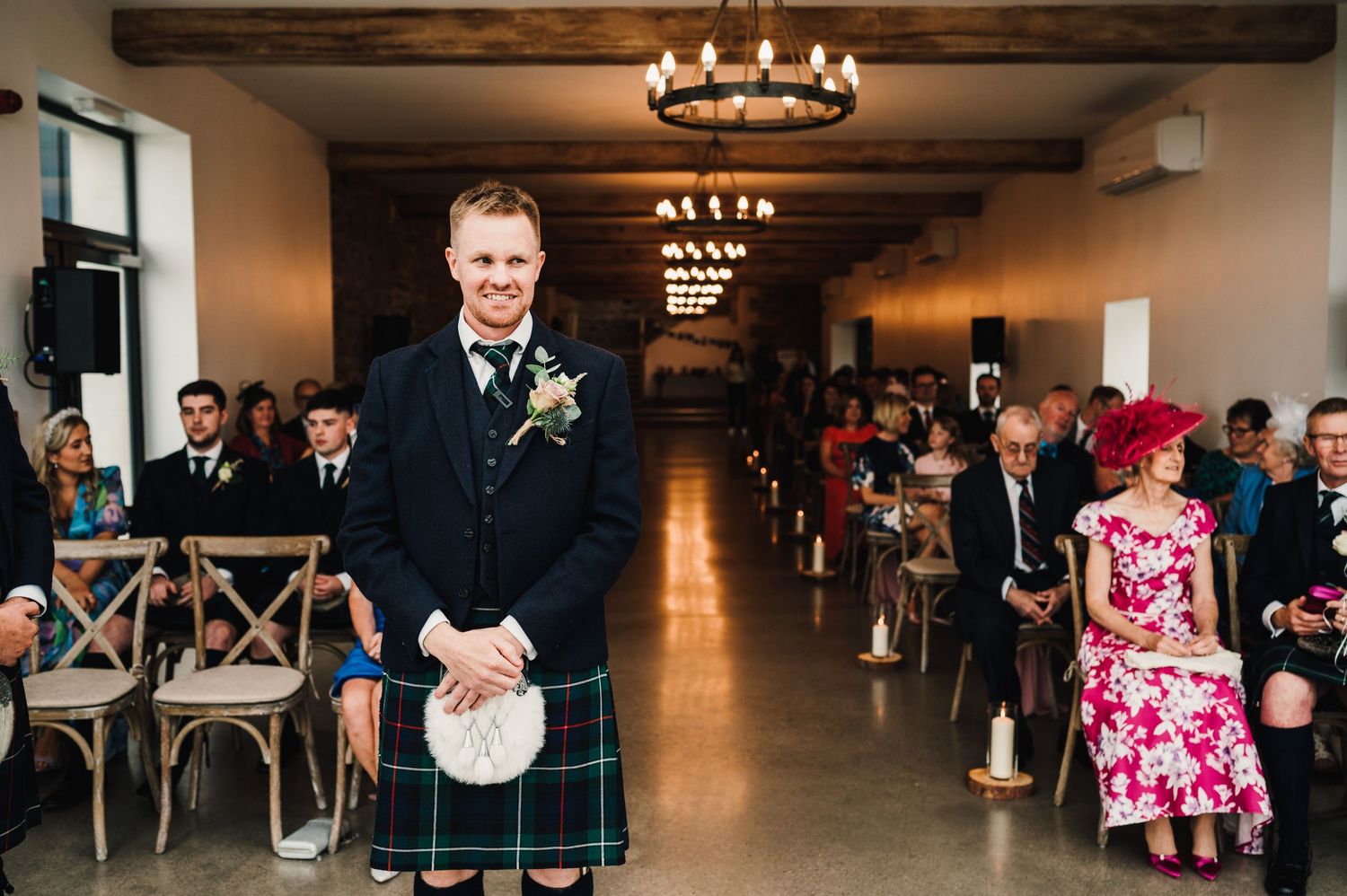 Traditional Scottish wedding ceremony setup with wooden beams and chandeliers in an elegant indoor venue.