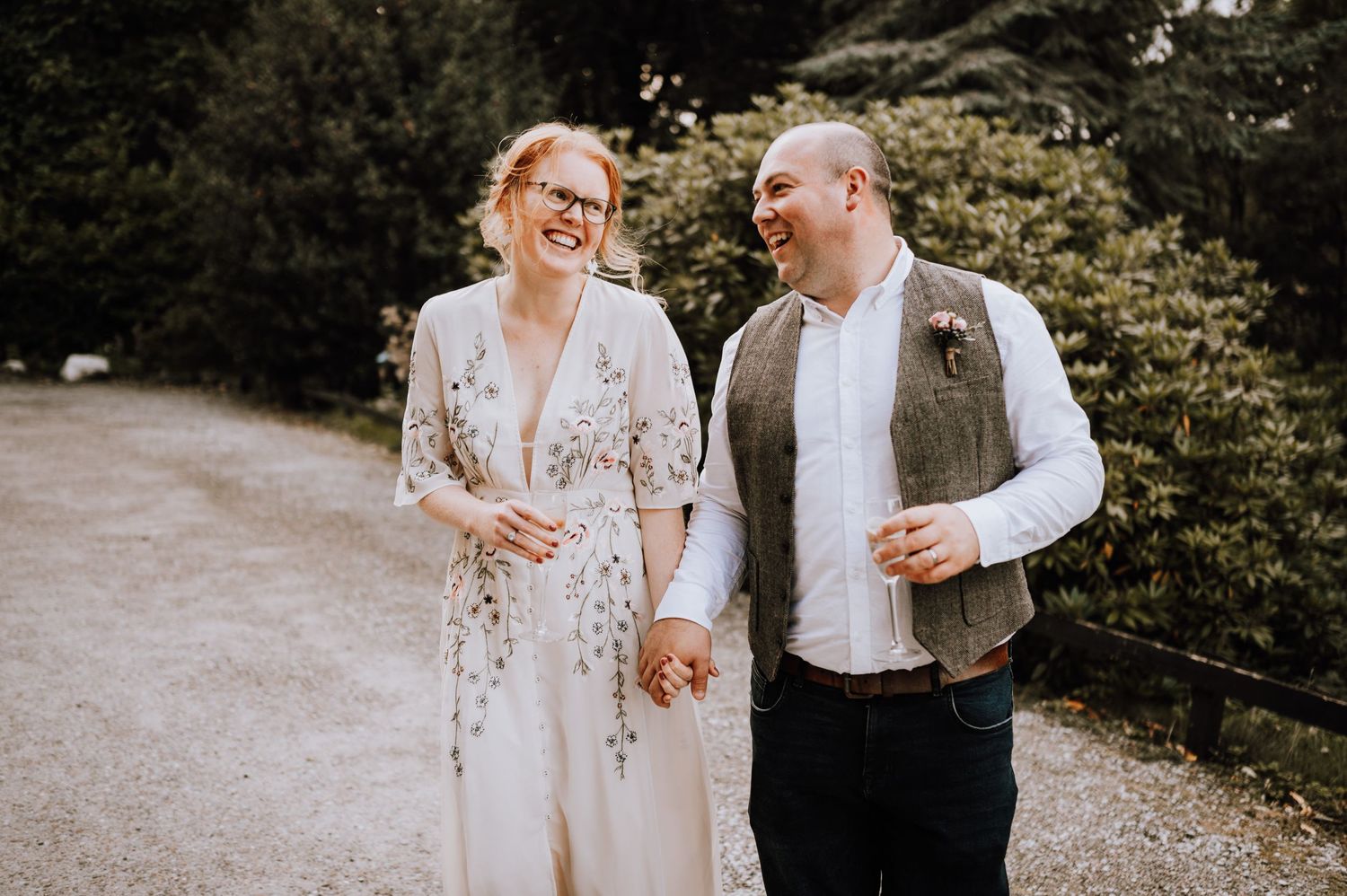 Happy couple sharing joyful moment while walking outdoors in casual wedding attire.
