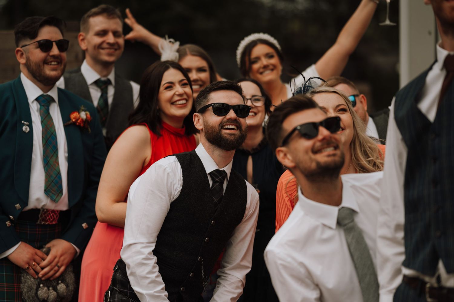 Wedding guests in formal attire enjoying celebration outdoors.