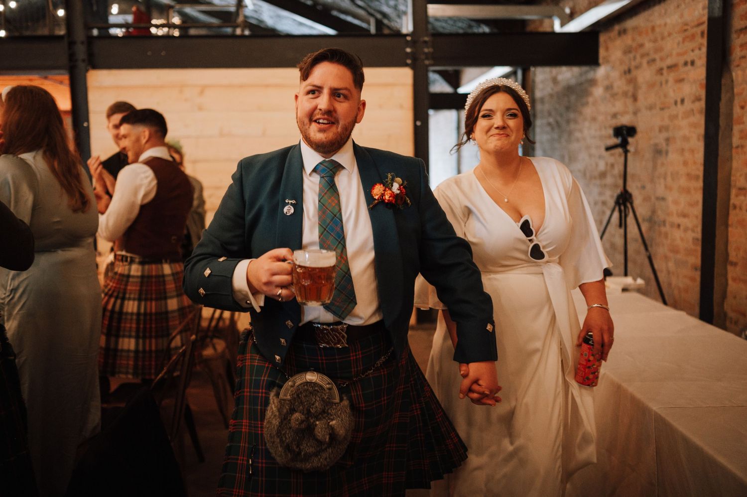Wedding celebration in industrial brick venue with guests enjoying festivities.