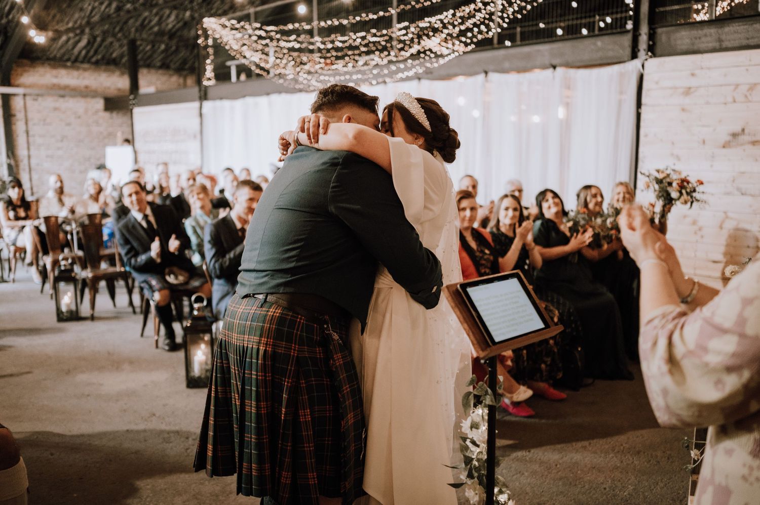 Emotional embrace during wedding ceremony while guests look on from their seats.