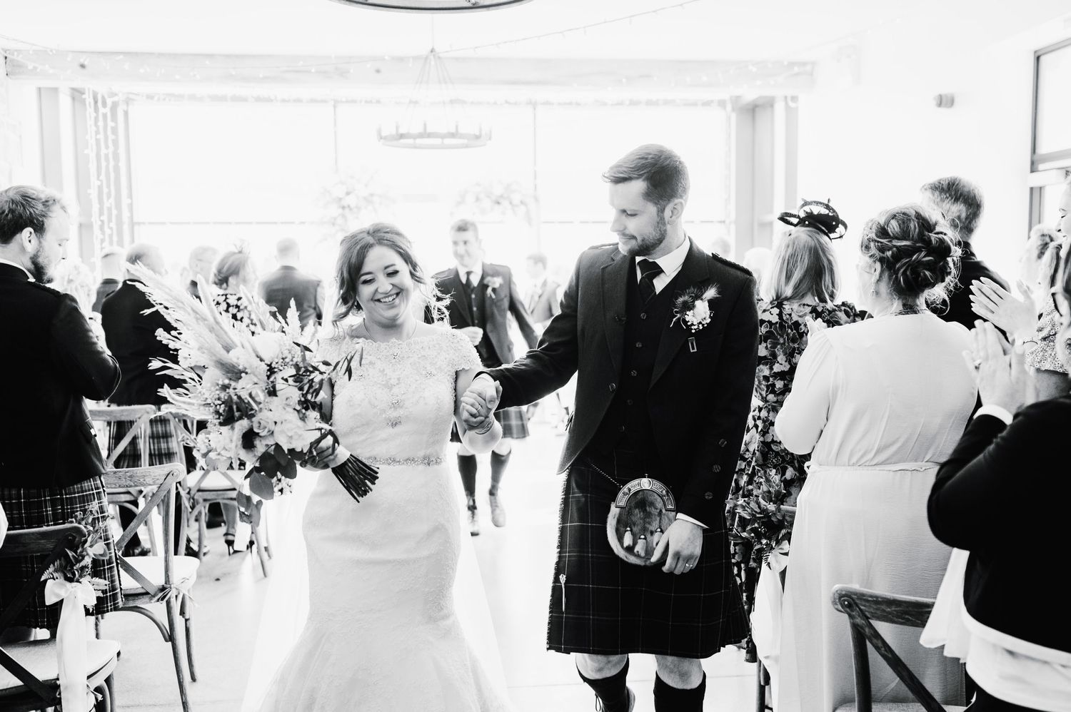 A joyful black and white capture of newlyweds celebrating after their Scottish ceremony.