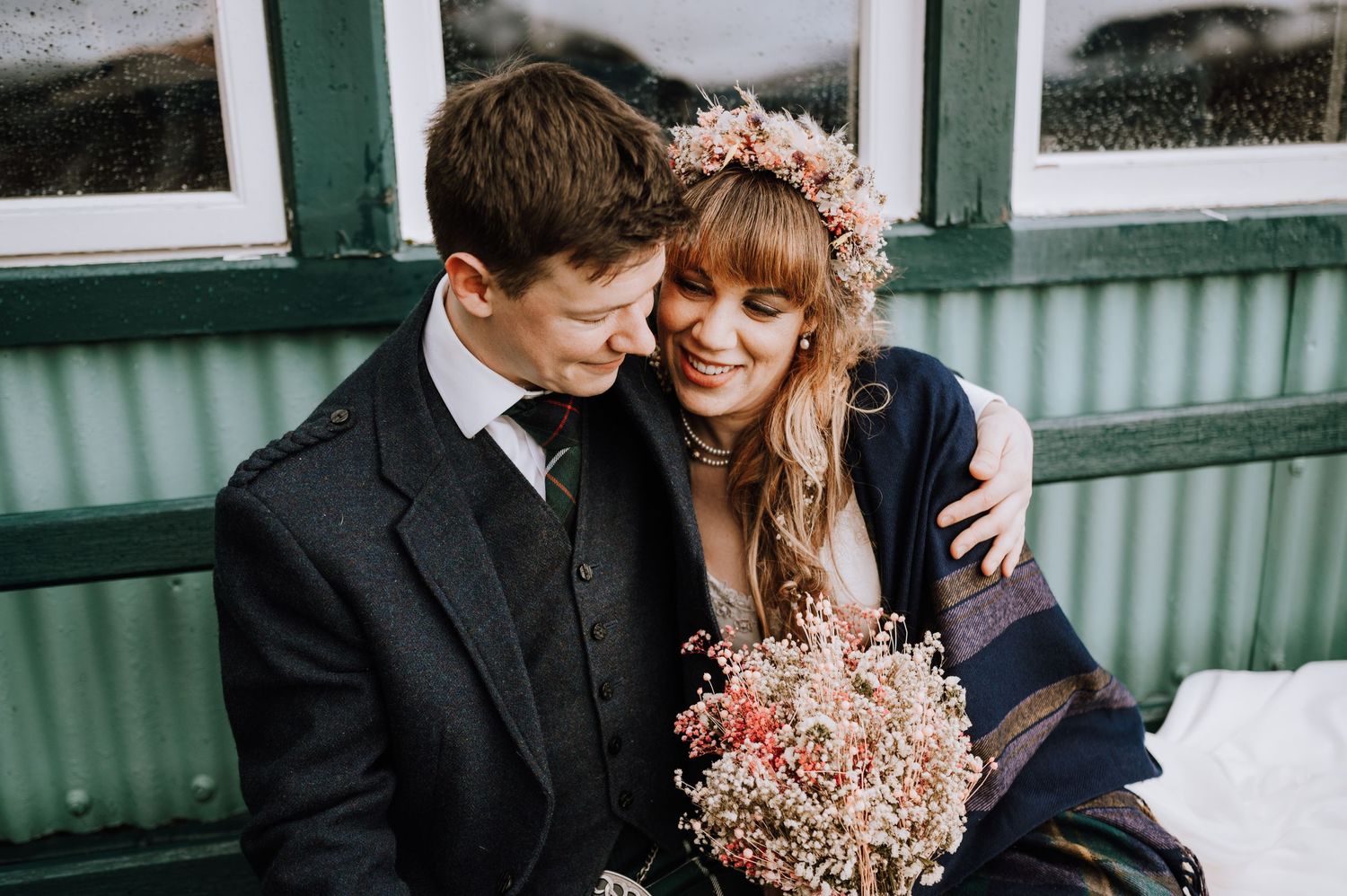 Couple embraces on vintage porch with dried flower bouquet and winter decor.