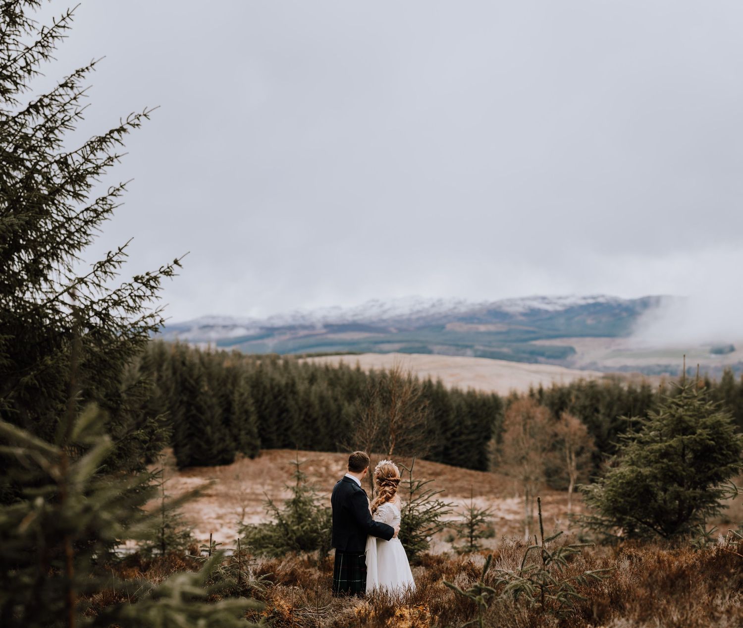 Couple celebrating their wedding day against stunning misty Scottish mountain vistas.
