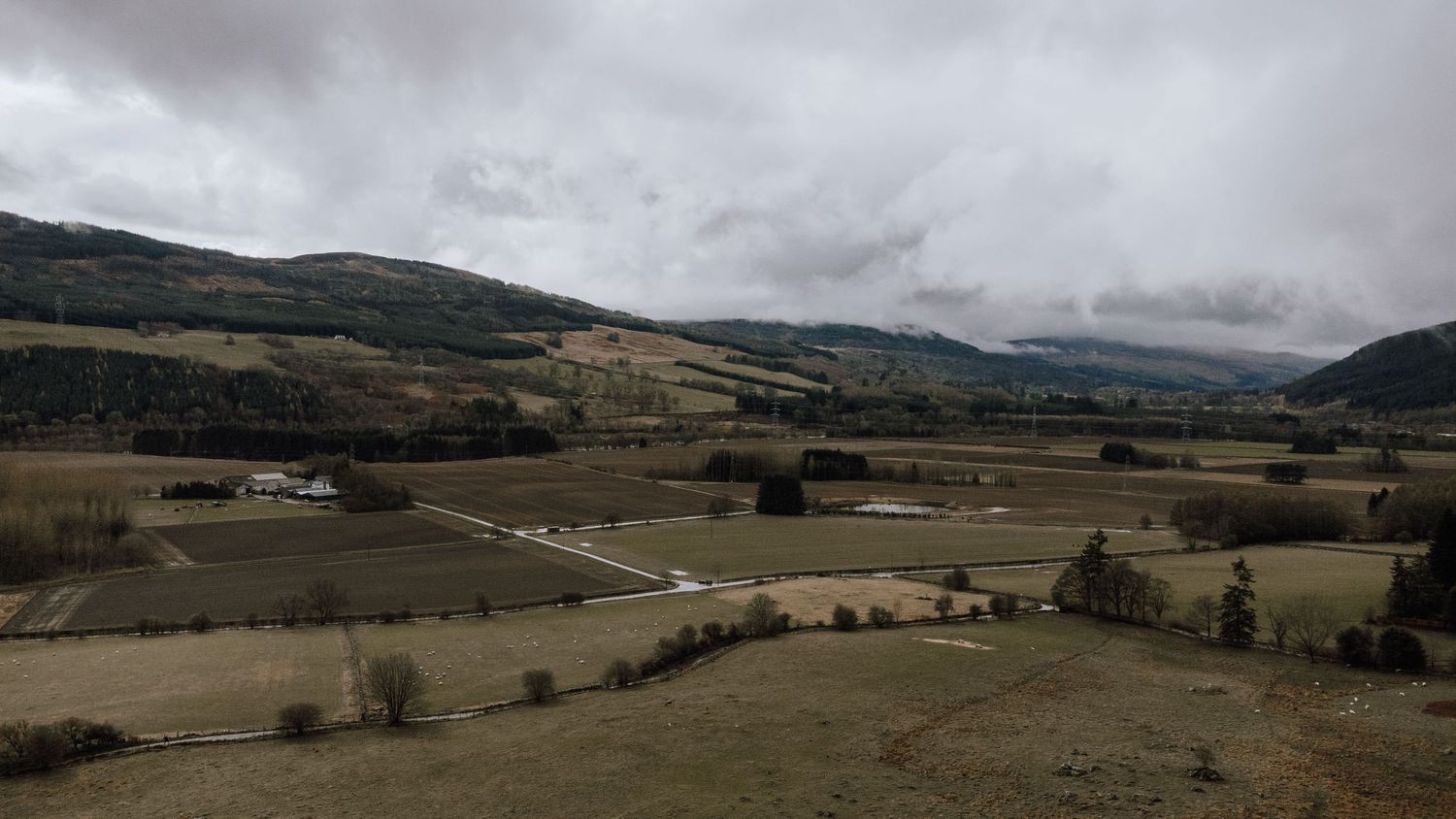 Misty mountain landscape with rolling farmland and scattered buildings in the valley.
