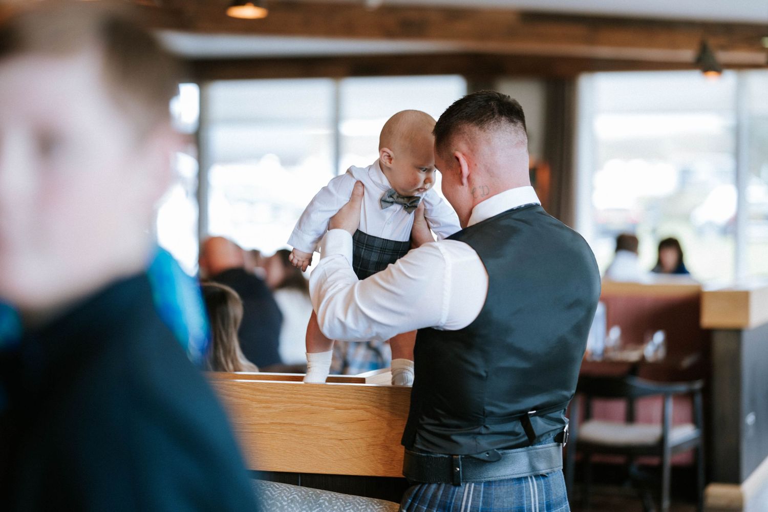Wedding party dancing and celebrating in a rustic venue with wooden beams and natural lighting.