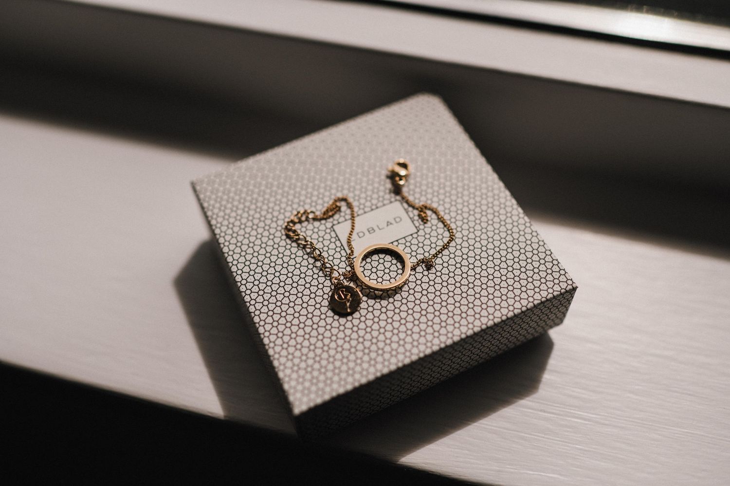 Delicate gold stethoscope charm jewelry displayed on a gray textured surface.