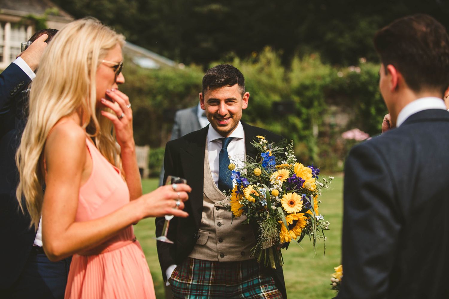 Guest in peach dress laughs while holding drink at Scottish-themed wedding.
