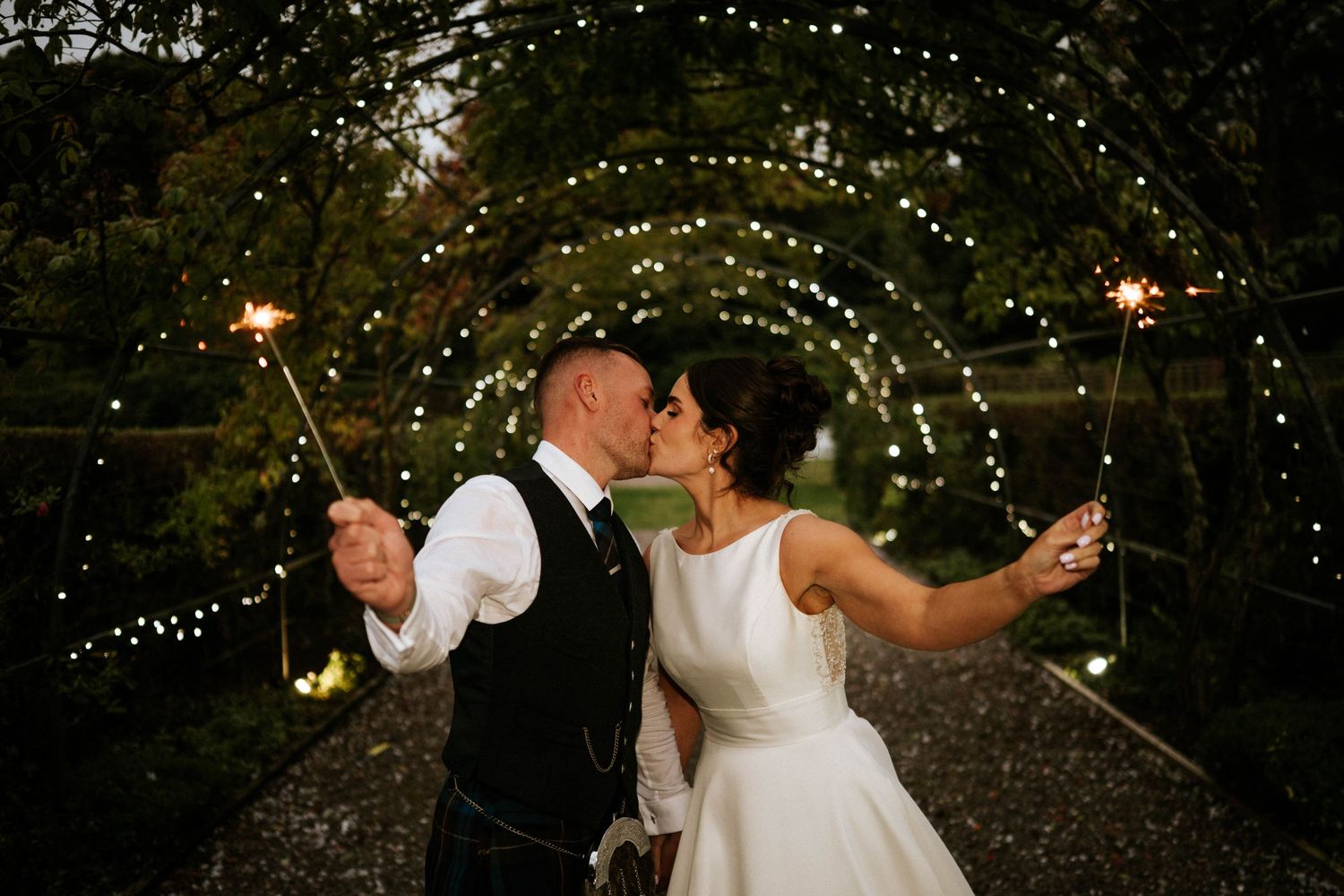 Evening wedding celebration under twinkling lights in a romantic garden setting.