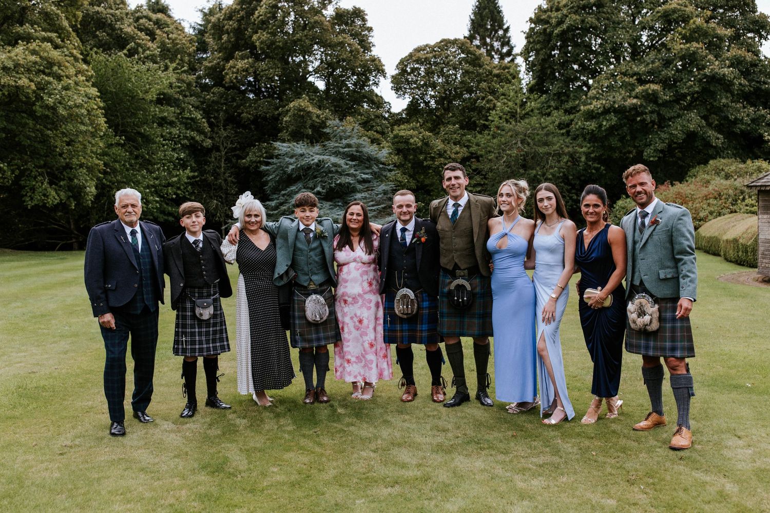 Wedding party poses for group photos on a lush green lawn.