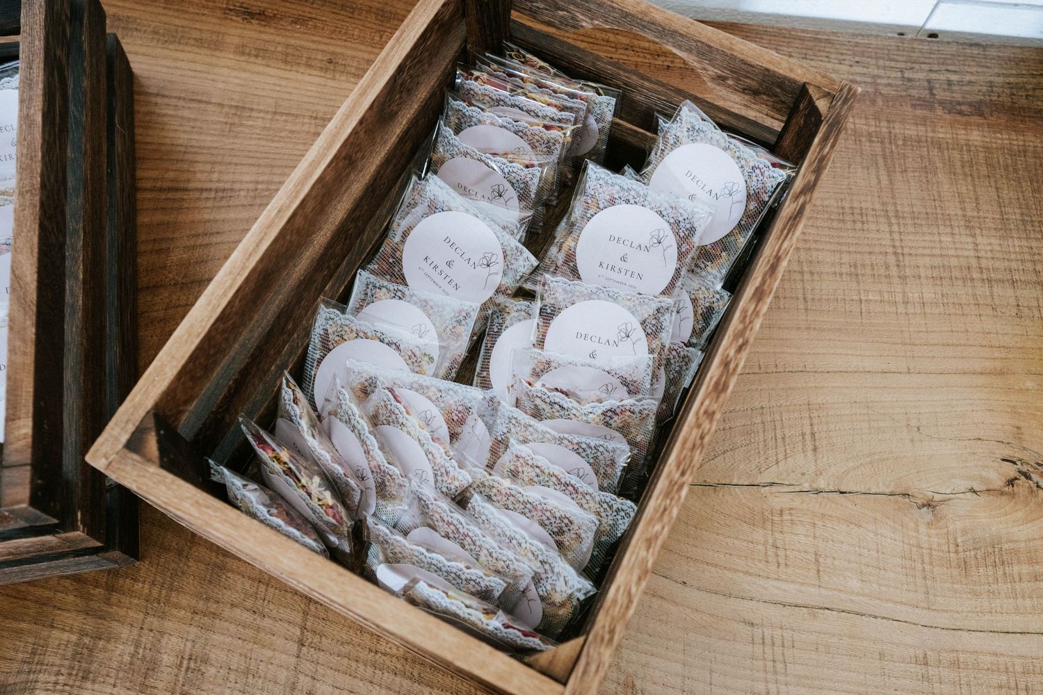 Wooden boxes filled with neatly arranged wedding favors and gift items on a rustic surface.
