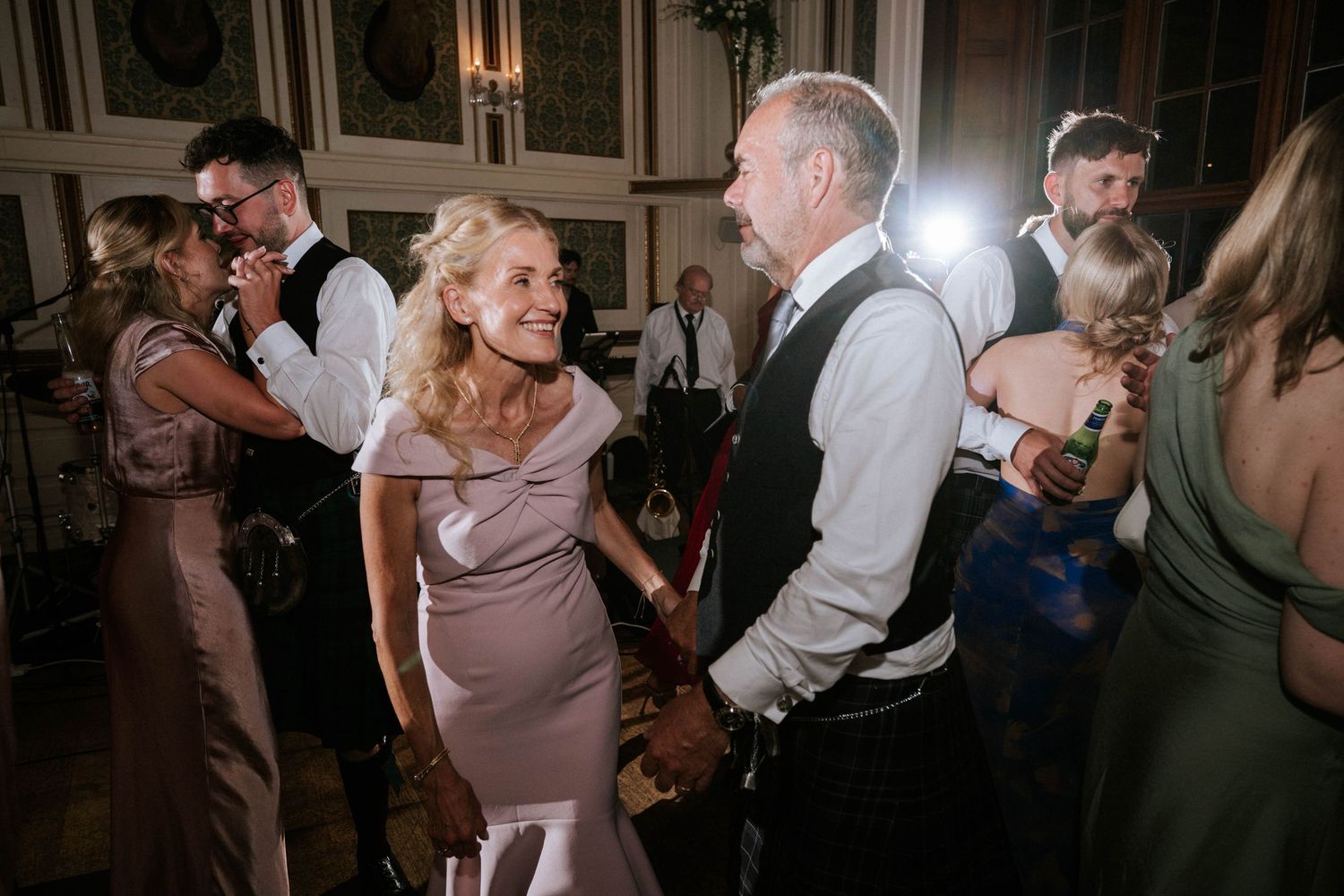 Wedding reception dance floor filled with guests celebrating in a dimly lit ballroom.