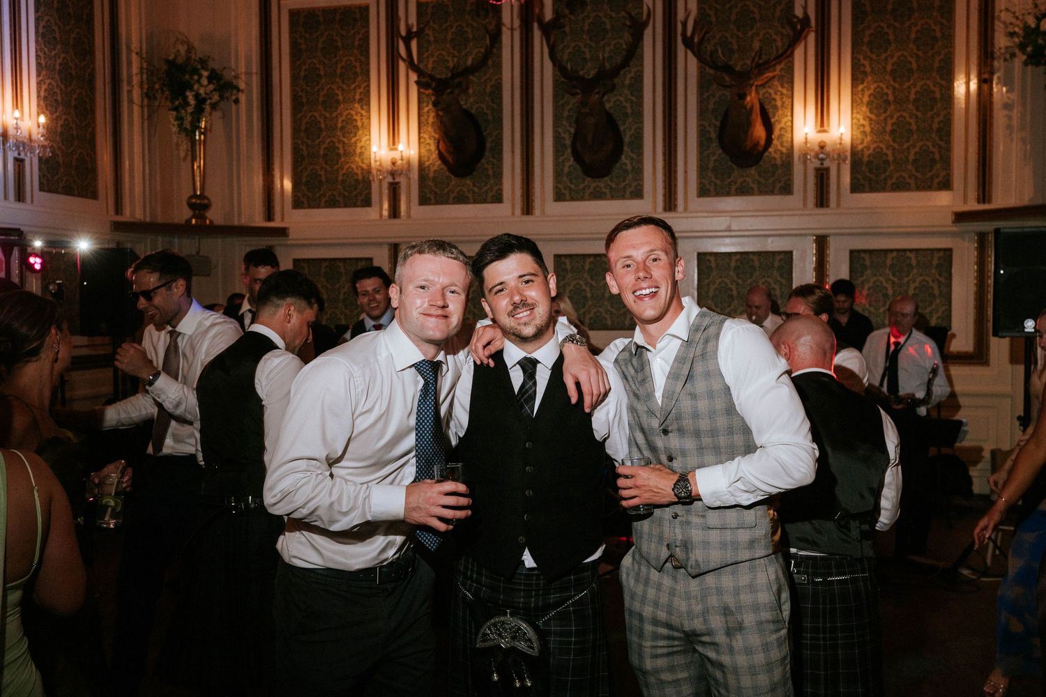 Dimly lit reception hall with guests celebrating on the dance floor.