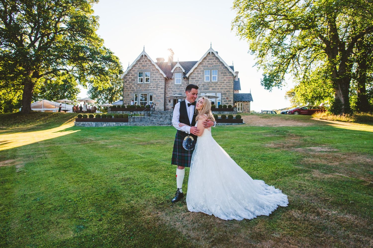 Scenic wedding venue with stone buildings and green lawns during golden hour.