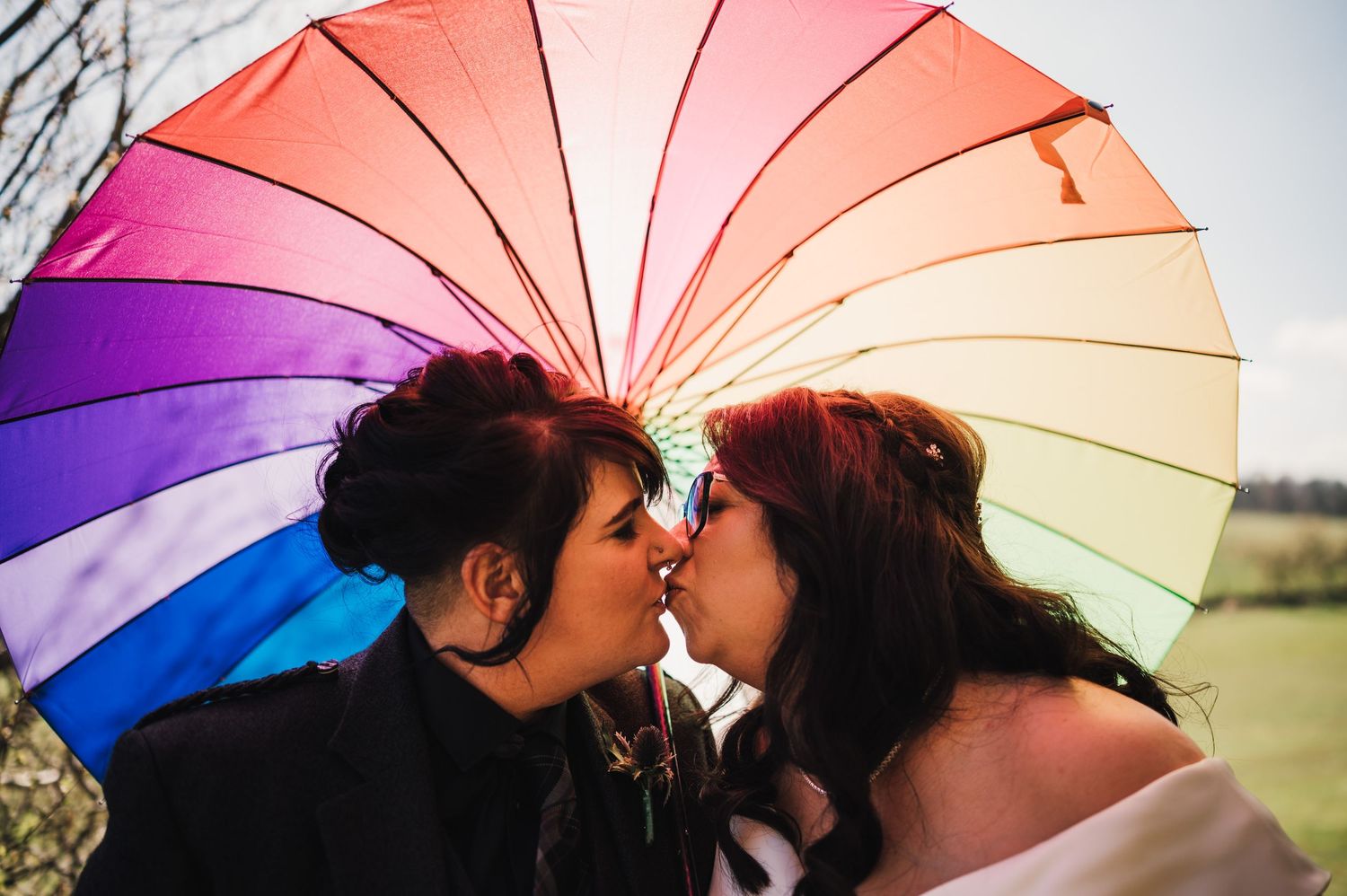 Logie House Wedding Photography. A romantic moment shared under a vibrant rainbow umbrella during a wedding photoshoot.