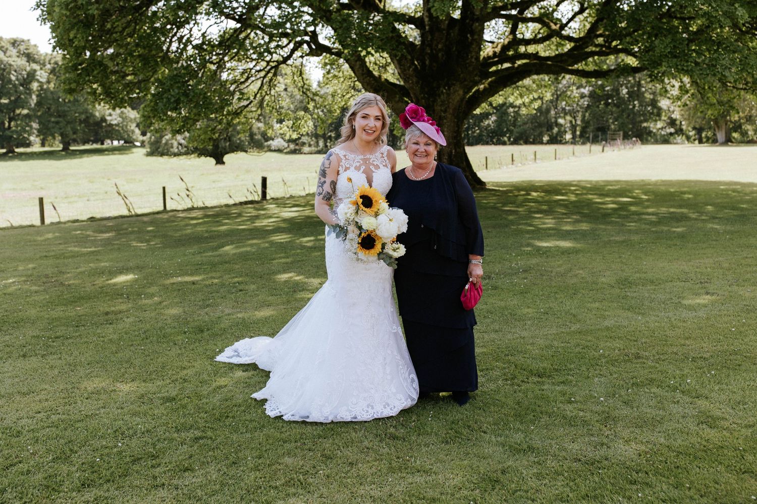 Wedding group poses for outdoor portraits under large tree branches.
