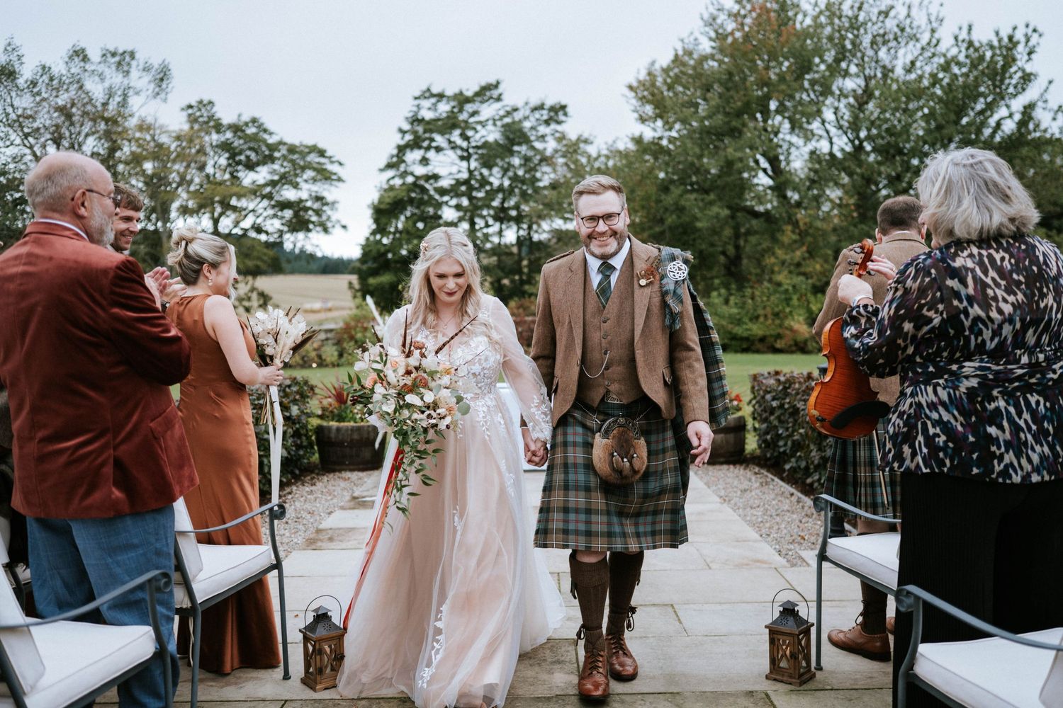 Outdoor wedding celebration with guests mingling in a garden setting.