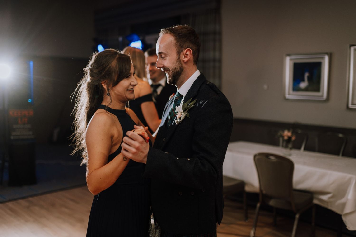 Couple shares an intimate dance moment under warm lighting at their reception.