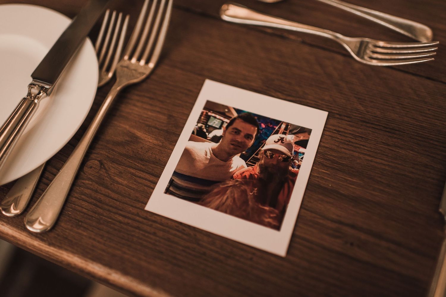 Polaroid photo placed on wooden table with place setting and silverware.