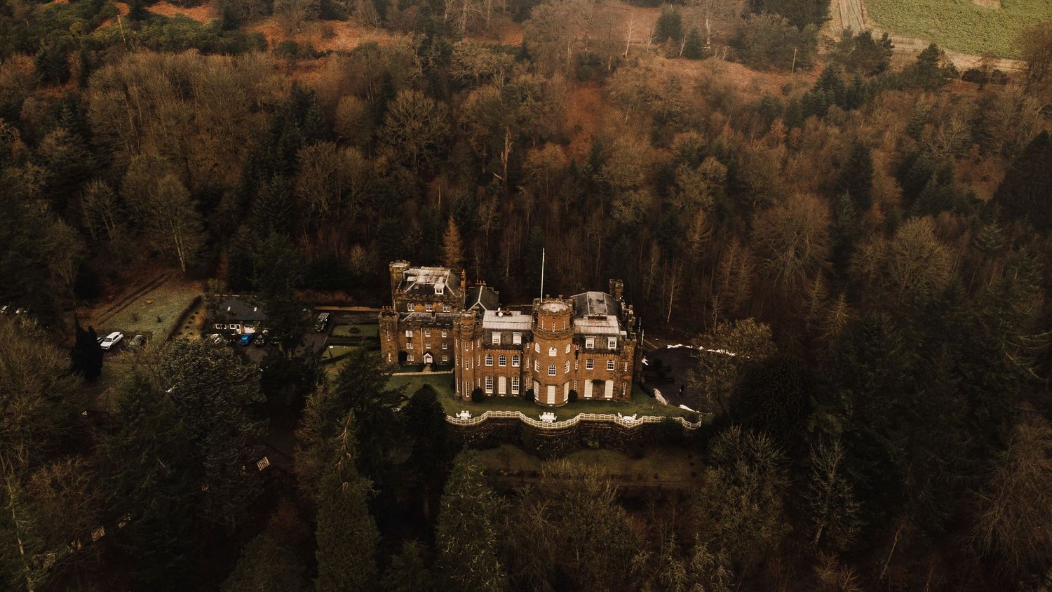 Aerial view of a grand Victorian mansion surrounded by autumn trees.