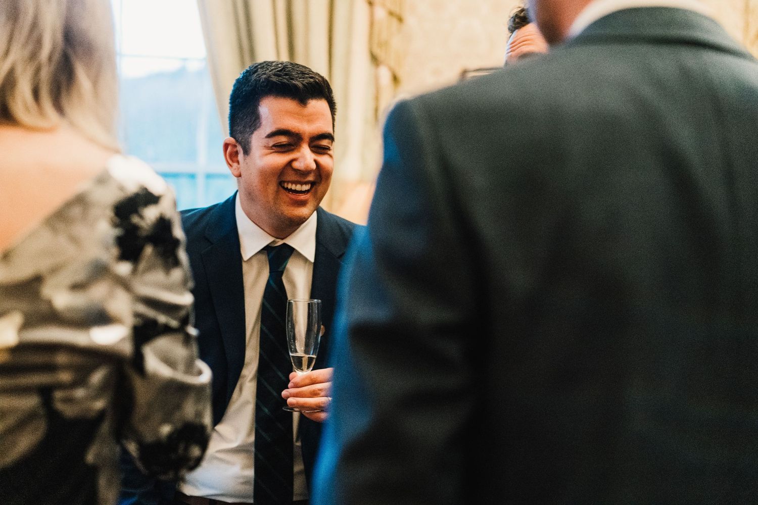 A guest shares a laugh during conversation at an elegant indoor reception.