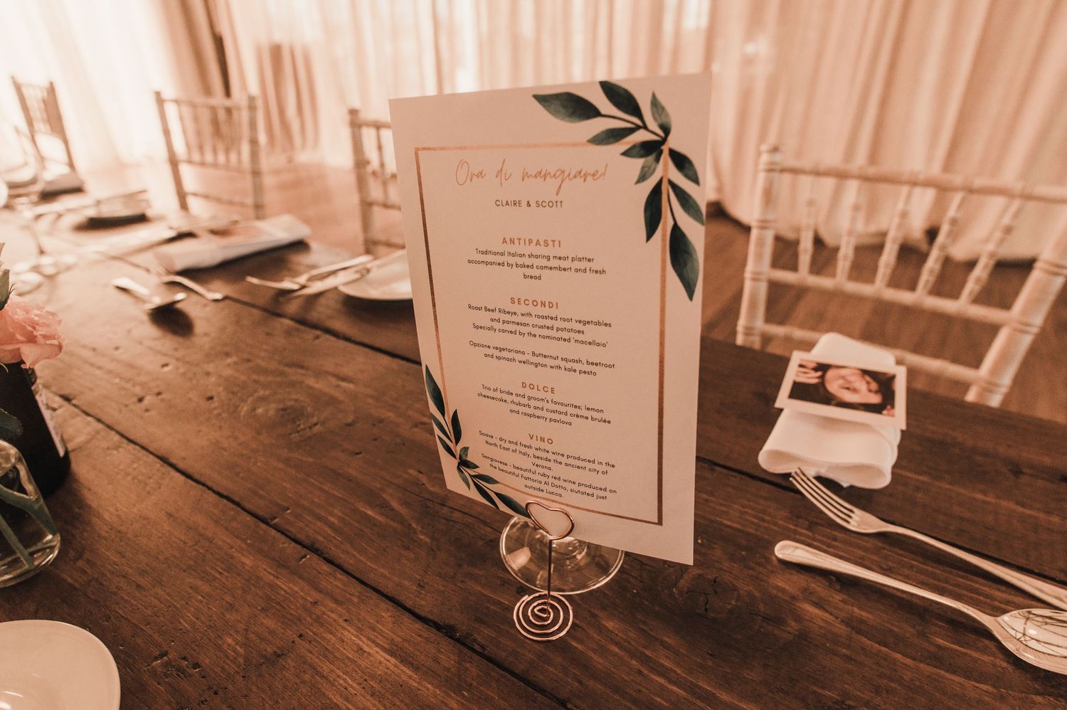 Elegant wedding menu card with floral design displayed on wooden table setting.